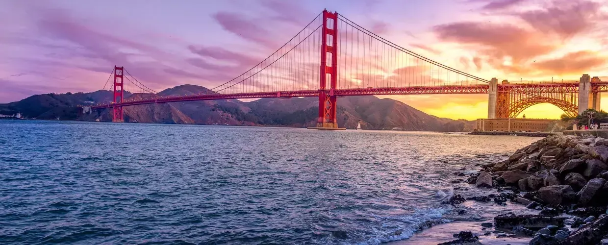 El puente Golden Gate al atardecer con un cielo multicolor y la Bahía 贝博体彩app en primer plano.